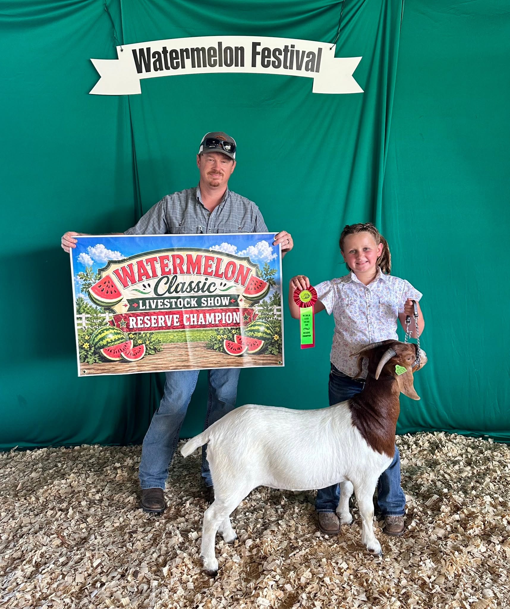 A man and a girl standing by a white goat. Watermelon Festival. Watermelon Classic Livestock Show Reserve Champion.
